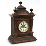 An Edwardian Gothic style oak mantle clock, the white enamel dial with Roman numerals and fitted