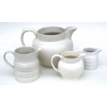 A group of four cream glazed jugs, the largest 23cms (9ins) high.