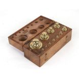 A set of twelve brass weights from 1 gram to 500 grammes in a fitted wooden block with hinged lid,