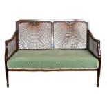 A bergere two-seater sofa with single caned sides and back, 114cms (45ins) wide.