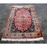 A Persian woollen hand knotted rug with central design within stylised borders, on a cream ground,