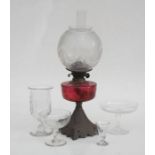 An oil lamp with cranberry glass reservoir and acid etched shade, 56cms (22ins) high; together