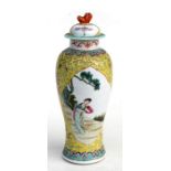 A Chinese baluster vase and cover decorated with figures on a yellow ground, the cover with a dog of