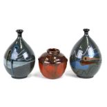 A pair of glazed earthenware art pottery vases of abstract decoration, each signed above the base