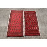 Two similar Persian Baluch woollen handmade rugs with geometric design on a red ground, each