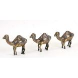 Three heavy brass Cairo ware camels with silver Arabic script overlay, each 10cms (4ins) high (3).