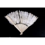 A 19th century Chinese carved ivory and feather brise fan, 23cms (9ins) long.
