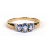A 9ct gold ring set with three tanzanites flanked by four diamonds, approx UK size 'S'.