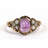 A 9ct gold ring set with a central amethyst cabochon flanked by seed pearls, approx UK size 'N'.
