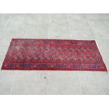 A Persian Hamadan runner with repeated geometric design on a red ground