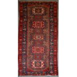 A Persian Azari hand knotted woollen runner with five stylised guls within floral borders, on a blue