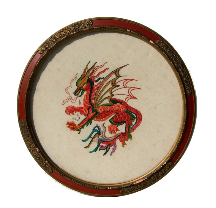 A circular needlework panel depicting a dragon, framed and glazed. 34cm (13.25 ins ) diameter