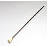 A carved bone back scratcher in the form of a hand on a turned wood handle, 40.5cms (16 ins) long.