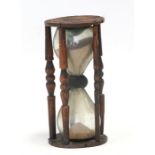 An hourglass sand timer in a treen frame, 20cms (8ins) high.