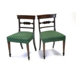 A pair of Regency mahogany dining chairs with carved back rail, overstuffed seats, on tapering