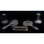 A three-piece silver backed dressing table set comprising a hand mirror and two hair brushes with