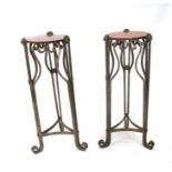 A pair of wrought iron plant stands with mahogany circular tops; together with a marble topped plant