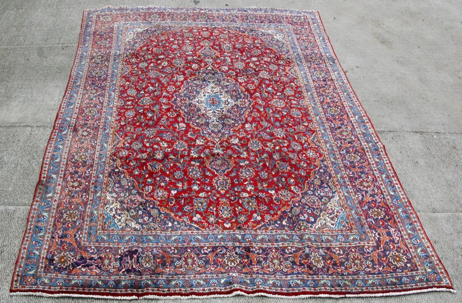 A Persian Mashad woollen hand knotted carpet with central floral medallion within floral borders