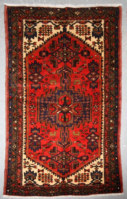 A Persian Hamadan hand knotted woollen rug with stylised design within borders, on a red ground, 159