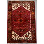 A Persian Hamadan hand knotted woollen rug with stylised central medallion within borders, 144 by
