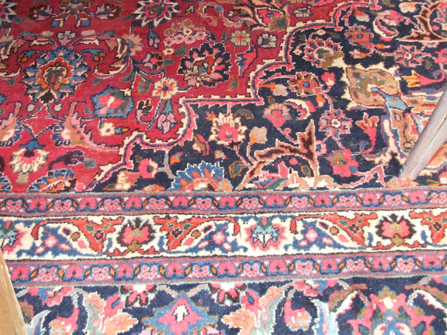 A Persian Kashan hand knotted woollen carpet with central floral gul within floral borders, on a red - Image 3 of 4