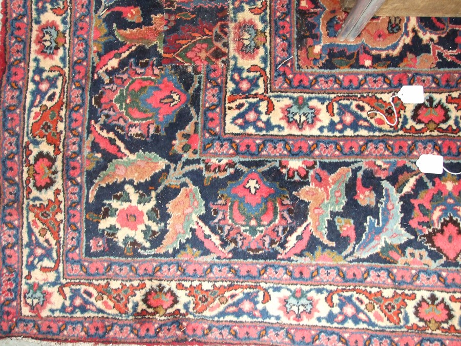 A Persian Kashan hand knotted woollen carpet with central floral gul within floral borders, on a red - Image 2 of 4