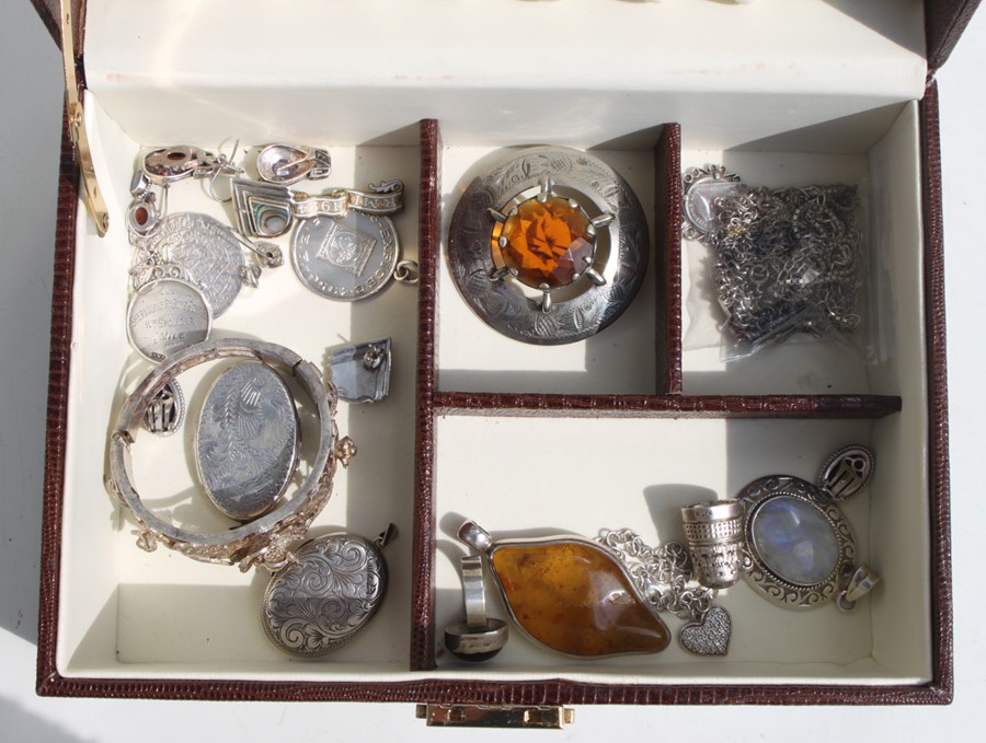 A faux crocodile jewellery box containing silver brooches, lockets, pendants, earrings and other