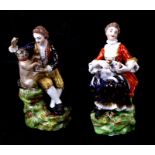 A pair of Staffordshire figures depicting a young man and a young woman, both holding small dogs,