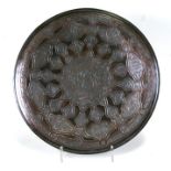 A large Islamic copper charger with white metal decoration including central Islamic script within