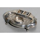 A silver desk stand with two-division stamp box and well for inkwell, standing on paw feet,