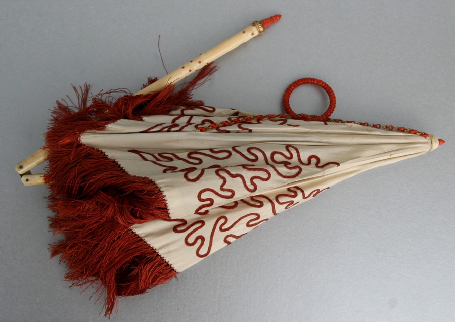 A 19th century ladies folding parasol, the silk canopy with coral coloured wavy line embroidery