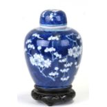 A Chinese blue & white ginger jar and cover of ovoid form decorated with prunus, on a hardwood