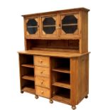 A stripped pine dresser, the glazed upper section above a central bank of four drawers flanked by