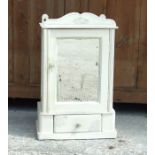 A distressed painted wall cupboard, the mirrored door above a single drawer, 36cms (14ins) wide.