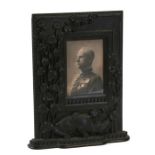 A Burmese carved wooden strut photo frame carved with a dragon amongst foliage, 26 by 33cms (10.25