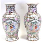 A pair of 20th century Chinese famille rose vases decorated with figures within panels, 46cms (