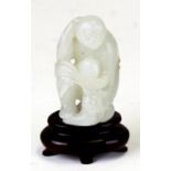 A Chinese jade figure in the form of a monkey holding a fruit, on an associated hardwood stand, 5cms