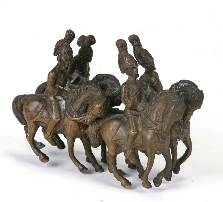 A bronze group depicting four guardsmen on horseback, 11cms (4.25ins) long.