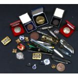 A quantity of whistles, commemorative coins, medallions, fountain pens and other items.