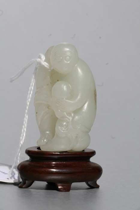 A Chinese jade figure in the form of a monkey holding a fruit, on an associated hardwood stand, 5cms - Image 3 of 9