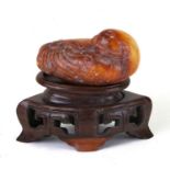 A Chinese russet jade figure of a quail mounted on a hardwood stand, 5.5cms (2.25ins) long.