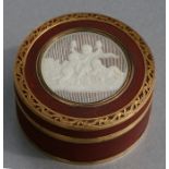 An 18th century red lacquer snuff box of circular form, the top with circular pierced ivory panel