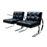 A pair of Andrew Martin design black leather and chrome mid century inspired armchairs (2).