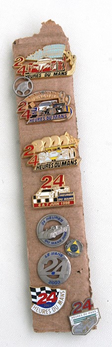 A collection of Le Mans 24-hour enamel pin and lapel badges.