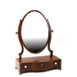 A 19th century mahogany serpentine fronted oval toilet mirror with three frieze drawers.