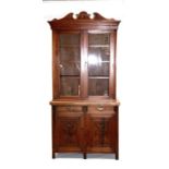 A late 19th century walnut bookcase on cupboard, the pair of glazed doors enclosing a shelved
