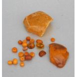 A group of loose butterscotch amber beads; together with two pieces of raw amber.