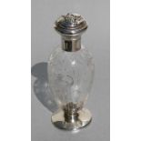An Edwardian silver mounted glass scent bottle, the lid decorated with a lady holding flowers,