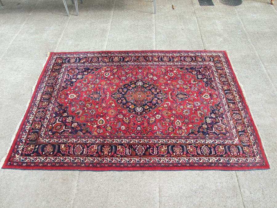 A Persian Tabriz rug with central medallion within foliate scrolls on a red ground, 210 by 305cms (