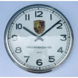 A Porsche themed wall clock, the white dial with Arabic numerals and Porsche shield, signed Porsche,